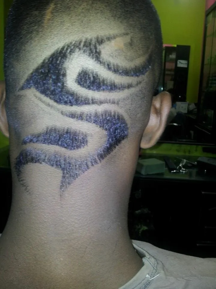 Back-of-head close-up showing an intricate freehand shaved-in pattern, with curved lines and a clean fade tapering down the neckline